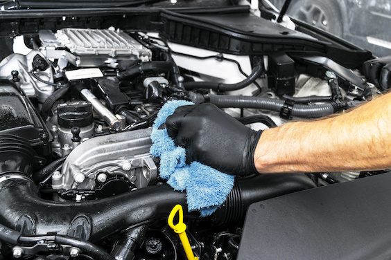 A man cleaning car engine with microfiber cloth