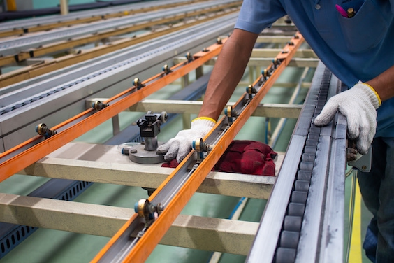 The technician cleaning conveyor belt in production line at factory plant